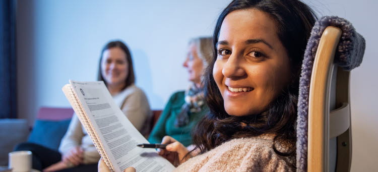 Gulistan som sitter och läser ett dokument tillsammans med två kollegor..