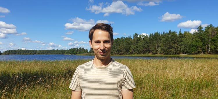 Dennis utomhus med vatten och en blå himmel i bakgrunden.