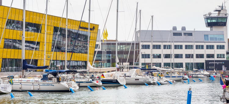 Bild på Linnéuniversitet som ligger i Ölandshamnen. Segelbåtar ligger i vattnet framför universitet. 